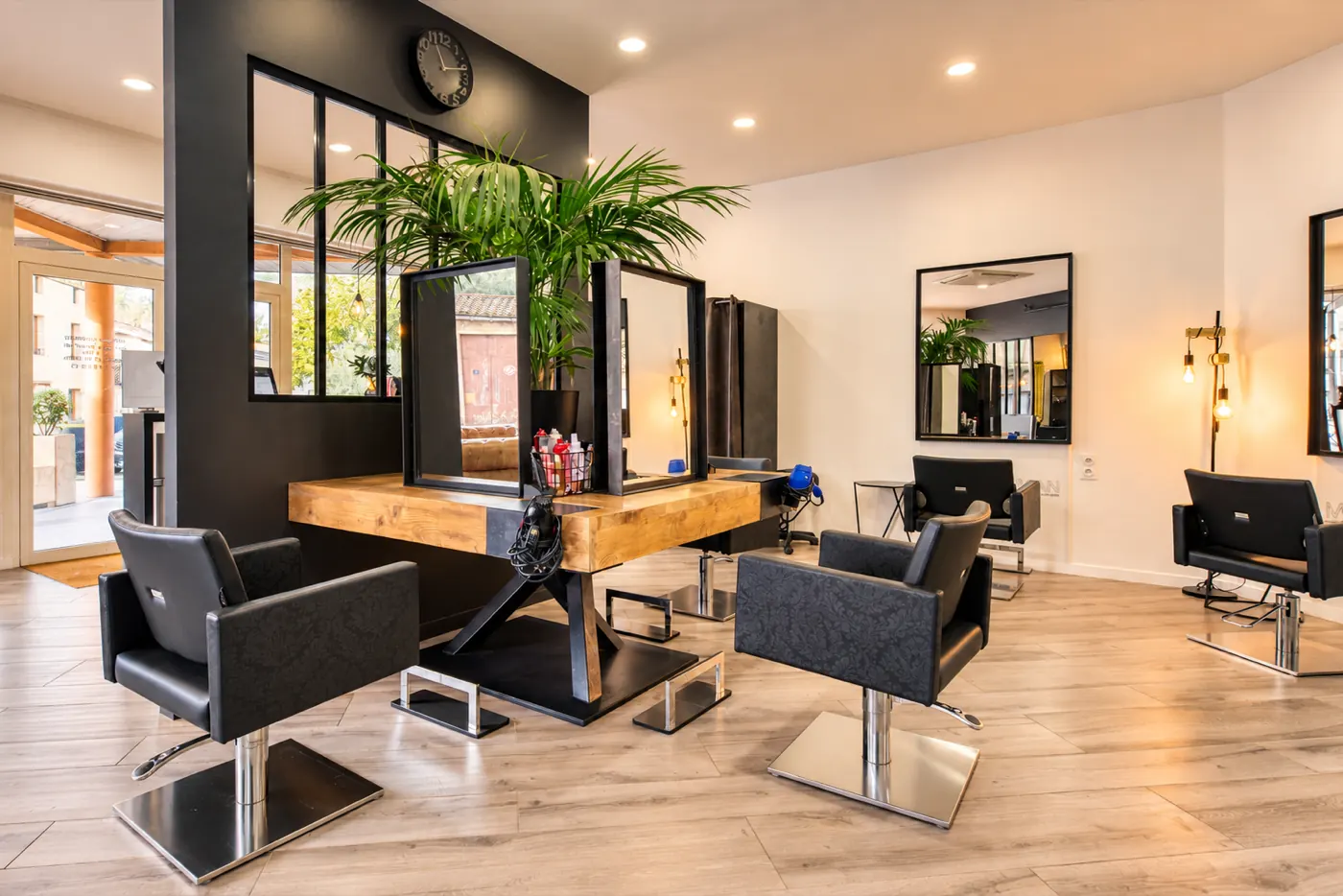 Poste de coiffure sous verrière et plantes vertes au salon Mickael Roman